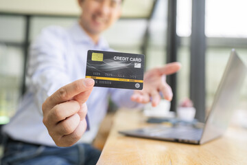 Businessman holding plastic credit bank card in hands at work in office closeup. Purchase and payment concept.