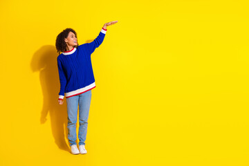 Cheerful young woman in casual attire posing against vibrant yellow background, showcasing a gesture and exuding joy