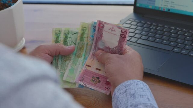 Close-up of a man's hand counting Qatari currency. High quality 4k footage