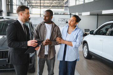 Car salesman showing vehicles to african american couple in dealership