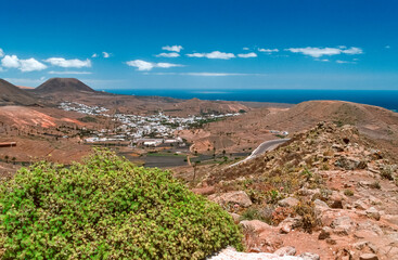 Eingescanntes historisches Farbfoto einer &Uuml;bersicht &uuml;ber die karge Vulkanlandschaft mit Siedlung, Bergen und der K&uuml;ste auf der kanarischen Insel Lanzarote