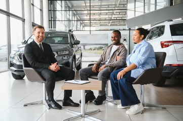 Car salesman advising couple buying new car in dealership