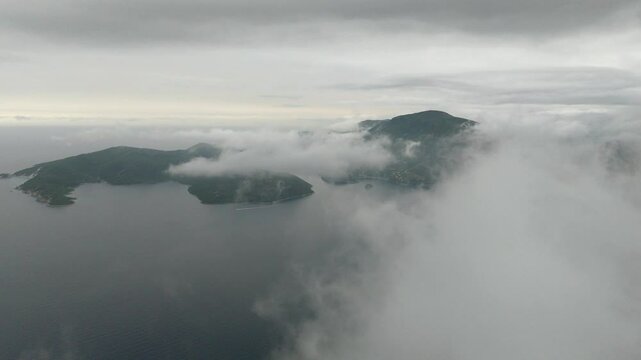 Aerial drone view of Ithaca flying through clouds foggy morning Greece Europe cinematic Vathy islands Ionian Mediterranean Sea 