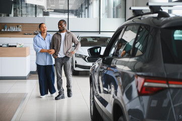 Couple choosing new car in dealership showroom