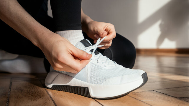 New light blue sport shoes being laced up for a workout session indoors