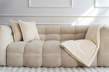 Modern white couch with cozy blankets and pillows in a bright interior space