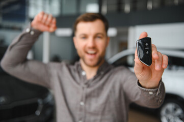 Happy customer showing new car key in dealership showroom