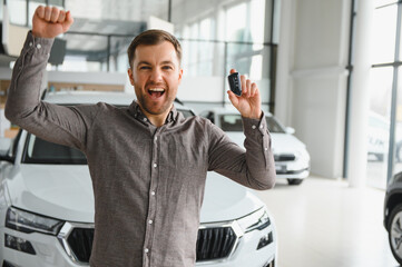 Excited customer holding new car keys and celebrating in showroom