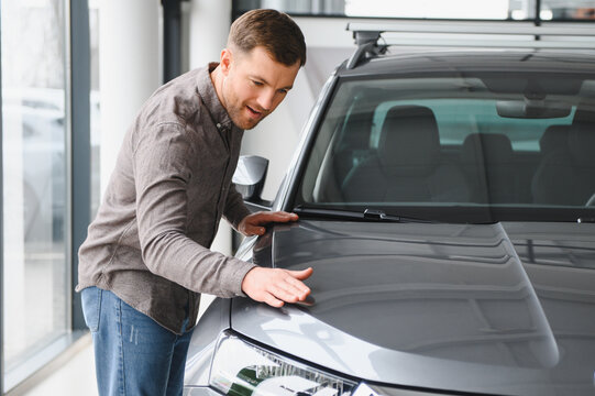 Man inspecting new car in showroom setting