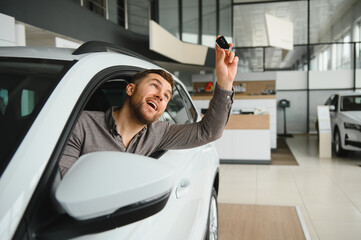Excited man choosing a new car in showroom