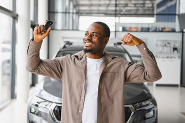 Happy customer showing new car key and celebrating in dealership