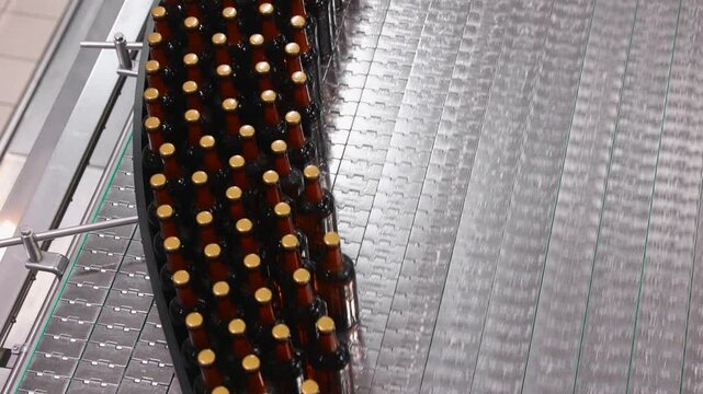 Top view automated beer bottling line with conveyor movement in modern brewery facility.