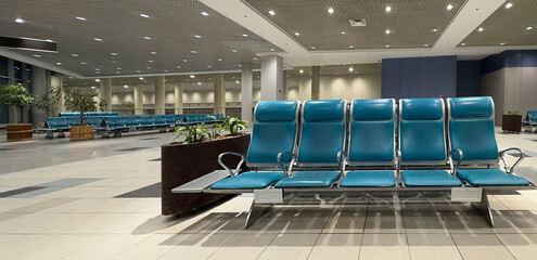 Spacious airport waiting area with empty chairs facing large windows.