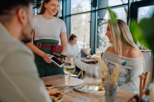 Woman paying restaurant bill with contactless payment using smartphone nfc technology