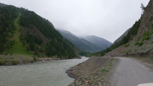 4k POV shot of a vehicle drive besides the river Chenab during a cloudy day as seen on the way to Udaipur in Pattan Valley, Lahaul, Himachal Pradesh, India. Scenic drive besides the river in Himalayas