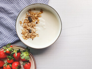 creamy yogurt with granola on light wooden table with space for text