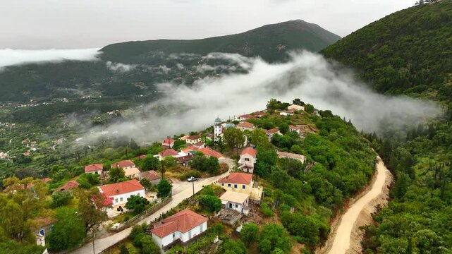Aerial drone view of Ithaca Mountain region foggy clouds summit villages church monastery Panagia Eleousia high up bays of blue water lush green water area Scenic veiws