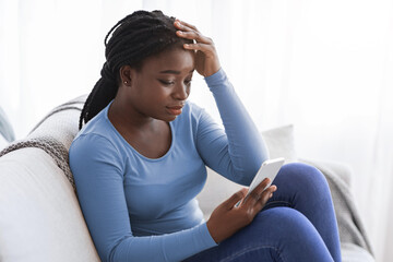 Worry African American Female Looking At Smartphone Screen At Home, Reading Bad Message, Upset...