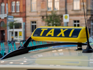 Taxi Sign on Yellow Cab with Urban Background