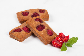 French cookie Financier. Chocolate almond cookies with raspberries. White background. Close-up