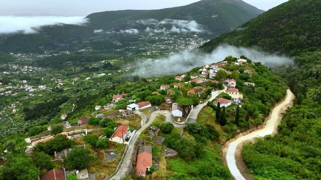 Aerial drone view of Ithaca Mountain region foggy clouds summit villages church monastery Panagia Eleousia high up bays of blue water lush green water area Scenic veiws