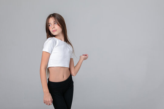 Beautiful teenage girl with long hair in black leggings and top in photo studio on white background. Model. Photo model. Photoshoot. Photo studio