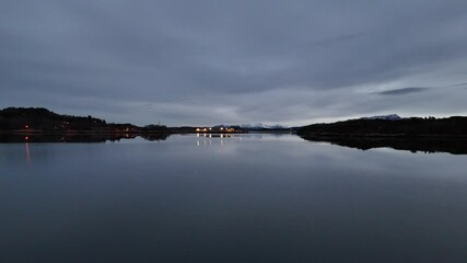 Low level drone shot of crystal clear water in Hendvaagen bay in Averoey city, Norway at dusk
