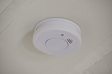 White smoke detector mounted on ceiling for fire safety in home