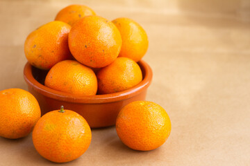 Fresh Tangerines in a Bowl on Brown Background