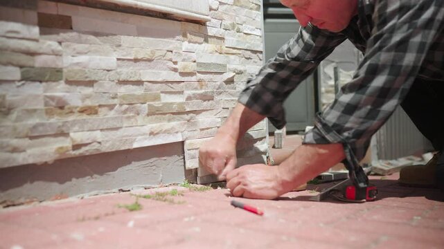 Construction worker installing stone veneer siding on house