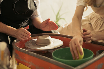 Potter showing apprentice how to use pottery wheel during class