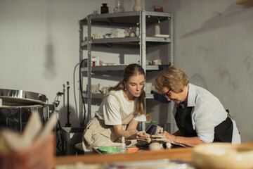 Senior potter teaching apprentice in pottery workshop