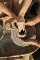Potter teaching student how to create clay pot on pottery wheel