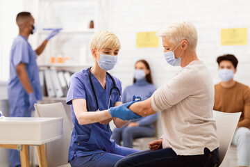 Obraz premium Covid-19 Vaccination Campaign. Senior Woman Receiving Coronavirus Vaccine Injection In Arm Sitting With Doctor In Hospital. Corona Virus Population Immunization, Covid 19 Cure Medicine And Treatment