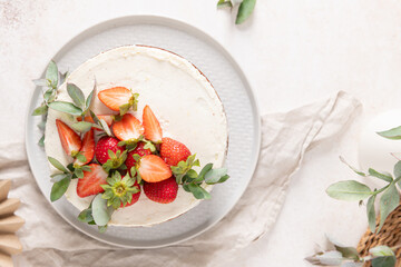 Overhead view of a delectable cake topped with vibrant fresh strawberries and artistic eucalyptus...