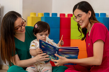 Pediatricians reading a book to baby girl in colorful office © Edgar1 BJ