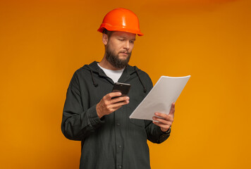 professional construction worker in helmet with smartphone and documents in hands isolated