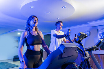 Couple working out in home gym, Personal trainer assisting client