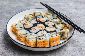 various kinds of sushi on a plate with chopsticks