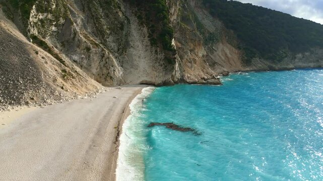Aerial drone footage of Myrtos Beach in Kefalonia, Greece showcasing stunning azure blue waters, white rocky sand beaches, and gentle waves&mdash;a scenic travel gem in Europe&rsquo;s Mediterranean.