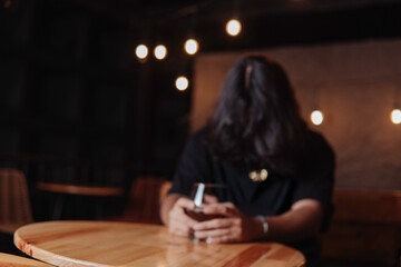 young latin man with long hair holding a glass of beer in a bar while looking at the camera