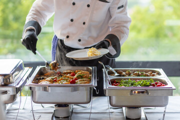 Chef serving a delicious buffet meal featuring grilled chicken, fresh vegetables, and flavorful...