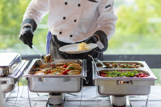 Chef serving a delicious buffet meal featuring grilled chicken, fresh vegetables, and flavorful sides at a catering event