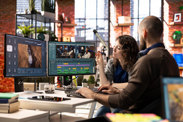 Plakat Man and woman filmmakers editing a video shoot in post production, using a modern tech setup and editing software for a creative video project. Modern workspace with dual monitors.