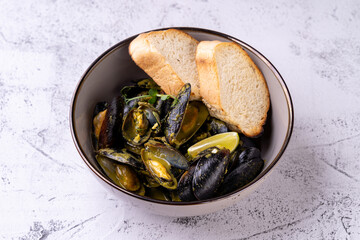 A bowl brimming with succulent mussels paired with crispy toasted bread and vibrant lemon slices invites diners to enjoy a delightful culinary experience