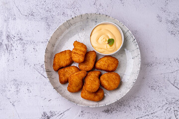 This delightful assortment showcases golden, crispy gastronomic treats arranged on a rustic plate, paired with a smooth and creamy dip, perfect for sharing or enjoying individually