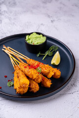 Savor the delightful presentation of gourmet skewers, expertly crafted and garnished, served alongside a zesty lime wedge and a smooth, creamy dip, inviting culinary exploration