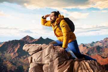 Hiker traveler pauses to admire the panoramic mountain scenery on the hill top, endless sky and...