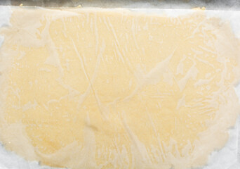 Top view of rolled out sugar cookie dough on a white countertop, process of making cut out sugar...