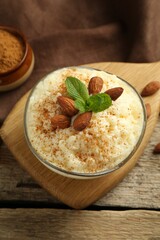 Delicious rice pudding with cinnamon, almonds and mint on wooden table, above view